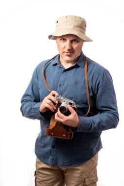 Sakallı orta yaşlı bir adamın portresi. Beyaz bir stüdyonun arka planında eski model bir kamera taşıyor. 