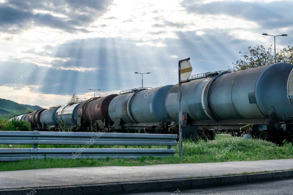 Railroad train of tanker cars transporting crude oil on the tracks under a beautiful dramatic sky.