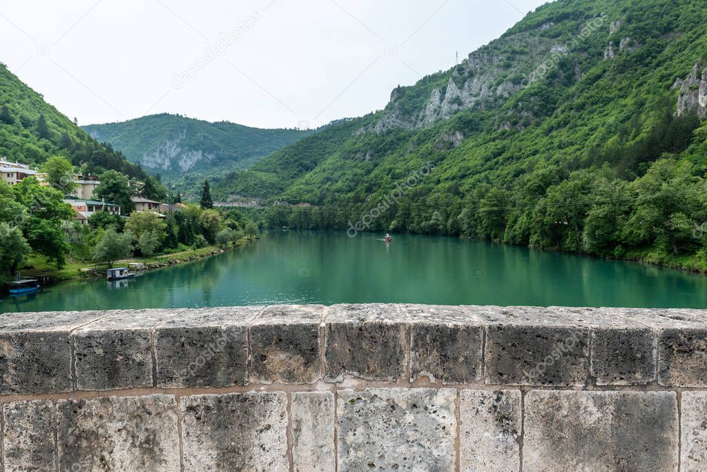 View on river Drina from the old Ottoman Mehmed Pasa Sokolovic Bridge in Visegrad, Bosnian mountains reflected in the river, Bosnia and Herzegovina.