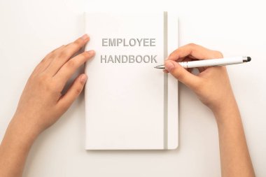 Beyaz Çalışan El Kitabı 'nı tutan kadın eller. Gri arkaplan, üst görünüm.