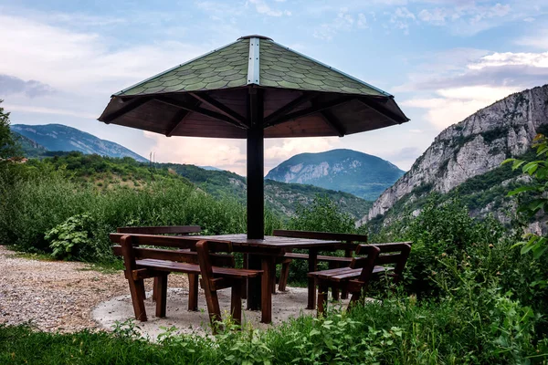 Table in the mountain resting place with a canopy from the rain and benches, a place to relax in nature. Resting place in Nature Park Sicevo Canyon