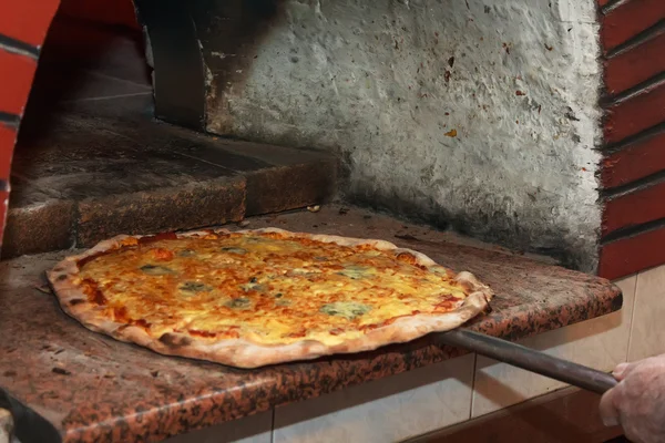 Szef kuchni umieścić pizzy w piecu — Zdjęcie stockowe