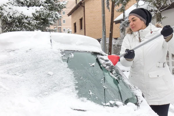 Vrouw schoonmaken sneeuw van de auto — Stockfoto