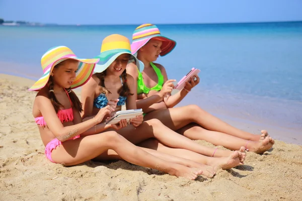 Meisjes met tablet op het strand — Stockfoto