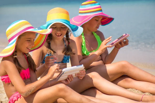 Meisjes met tablet op het strand — Stockfoto