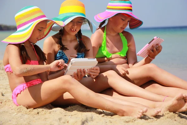 Meisjes met tablet op het strand — Stockfoto