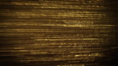 Abstract Gold Filaments Bursting Background/ 4k animation of an abstract wallpaper background of bursting gold filaments lines and particles sparkling with glimmer fx and depth of field seamless looping