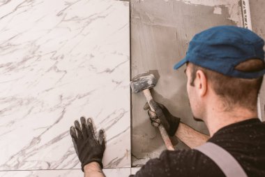 Tamirci banyonun duvarına seramik fayanslar yerleştiriyor.