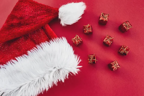 Kırmızı arka planda Noel Baba şapkası ve hediyeler.