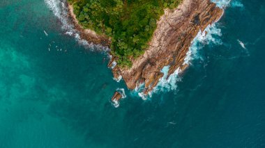 Beautiful aerial view of the ocean and tropical beach with palms and rocks.