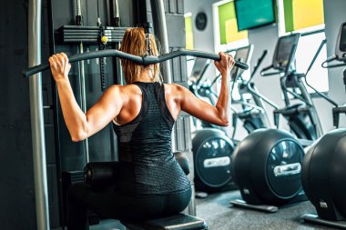 Spor salonunda halterle egzersiz yapan genç bir kadın..