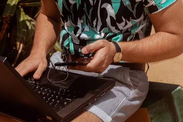 man digital nomad using laptop on the beach.