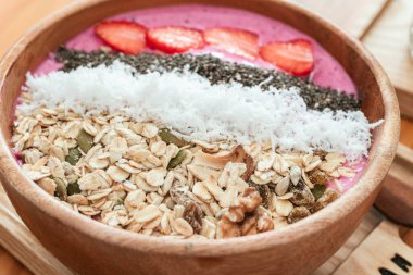 Lezzetli sağlıklı kahvaltı, granola, meyve, hindistan cevizi ve hindistan cevizli çilekli smoothie kasesi, açık arkaplanda estetik bir çekim..