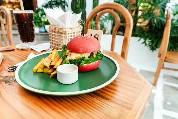 Vejetaryen burger, kırmızı çörek, patates kızartması, yeşil tabak, ahşap masa, sağlıklı vejetaryen yemeği..