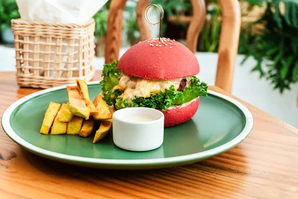 Vejetaryen burger, kırmızı çörek, patates kızartması, yeşil tabak, ahşap masa, sağlıklı vejetaryen yemeği..