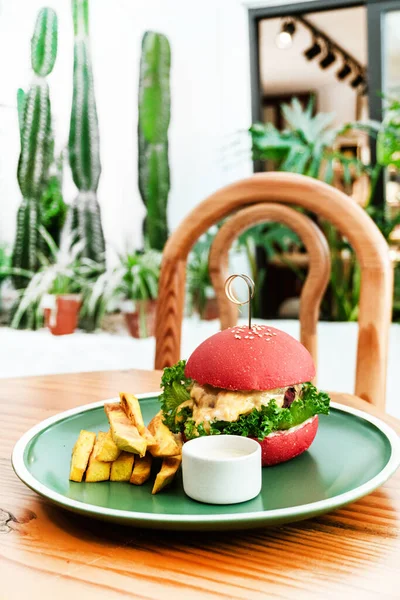 Vejetaryen burger, kırmızı çörek, patates kızartması, yeşil tabak, ahşap masa, sağlıklı vejetaryen yemeği..
