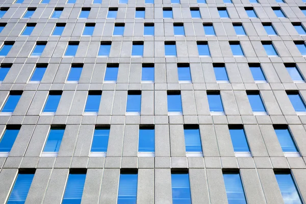 Concrete facade of office building with windows reflecting blue — Stock Photo, Image