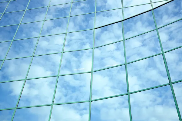 Riflessi di cielo blu e nuvole in facciata curva — Foto Stock