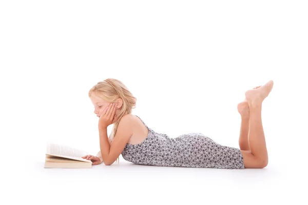 Young girl reads a book lying down — Stock Photo, Image
