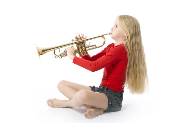 Ung flicka i rött spelar trumpet — Stockfoto