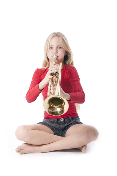 Ung flicka i rött spelar trumpet — Stockfoto