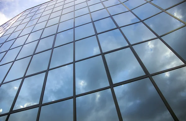 Reflexões de nuvens e céu azul na fachada do edifício moderno — Fotografia de Stock