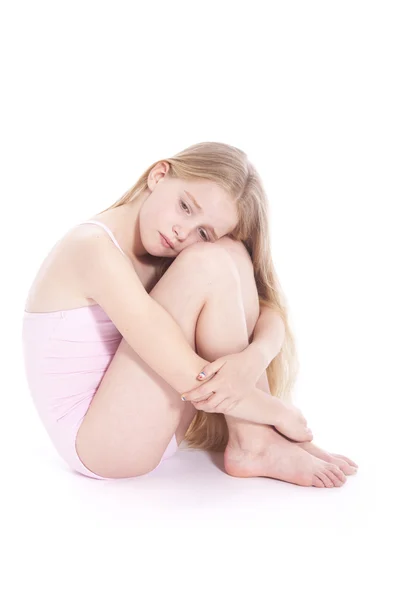 Young girl in pink with sad expression sitting on floor of studi Royalty Free Stock Images