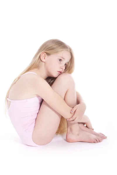 Young girl in pink with sad expression sitting on floor of studi Stock Photo