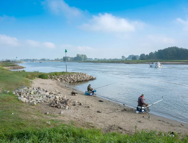 Twee mannen vissen op de oever van de ijssel in het binnenland onder de blauwe hemel — Stockfoto