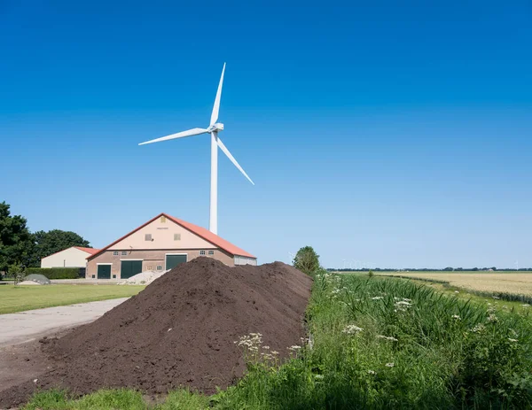 Celeiro fazenda em wieringermeer perto de turbina eólica sob céu azul — Fotografia de Stock