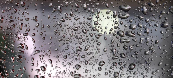 Барвисті дифузні негострі вогні за скляним вікном з краплями дощу — стокове фото