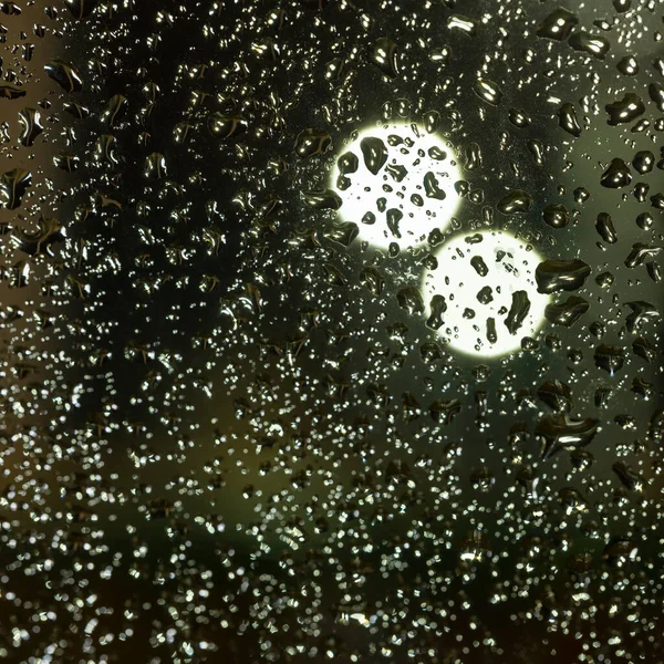 Fargerike, diffuse, uskarpe lys bak glassvinduet med regndråper – stockfoto