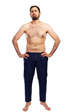 Hayal kırıklığına uğramış bir adam çıplak bir gövdeyle pantolonun içinde duruyor. Sportmenlik dışı bir figür. Tam yükseklik. Beyaz arka planda izole edilmiş. Dikey.