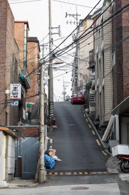 Tipik eski evleri ve park edilmiş arabaları olan modern Asya caddesi. Yol yukarı çıkıyor. Dikey. Seul, Güney Kore, 01-04-2018.