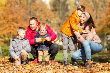 Sonbahar parkında üç çocuklu mutlu bir aile. Sevgi ve şefkat. Altın mevsiminde yürü.