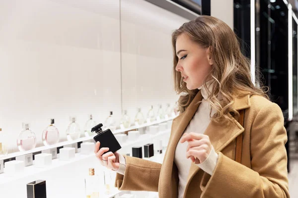 Молодая Женщина Выбирает Духи Магазине Улыбающаяся Красивая Блондинка Бежевом Пальто — стоковое фото
