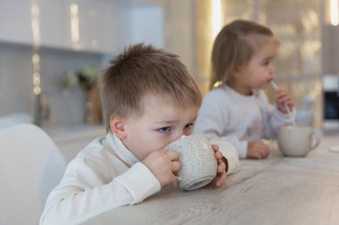 Küçük çocuklar masaya oturur ve fincanlardan içerler. Beslenme ve sağlık. Yakın plan..