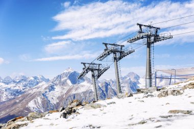 Açık güneşli bir günde kar kaplı dağlarda mavi bulutlu bir gökyüzünün zeminine karşı kaldırma mekanizması olan kablo araba. Aktif eğlence ve kış sporları. 