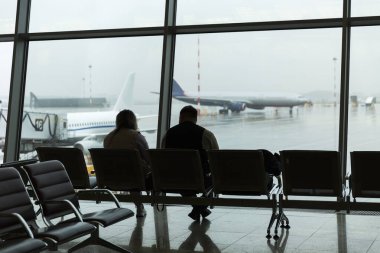 Havaalanı salonundaki yolcuların siluetleri uçağın arka planında. Seyahat ve iş seyahatleri.