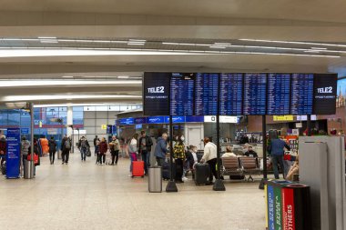 Uçuş çizelgesi ve kayıt gişesi olan büyük bir havaalanı salonu. İnsanlar yolculuk için hazırlanıyor. Moskova, Rusya, 10-28-2021.