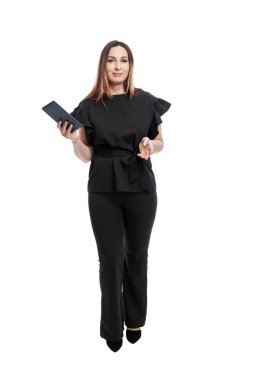 Takım elbiseli bir kadın elinde tabletle ayakta duruyor. Siyah pantolonlu ve bluzlu güzel bir esmer. İş başarısı. Beyaz arka planda izole edilmiş. Dikey. Tam yükseklik.