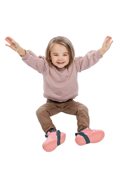 Маленькая Девочка Сидит Смеется Поднятыми Руками Симпатичный Ребенок Коричневых Джинсах — стоковое фото