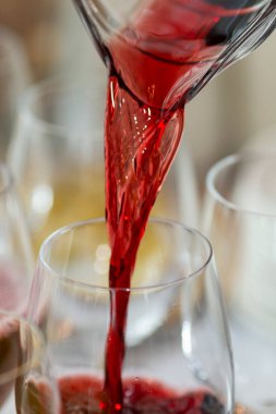 Kırmızı meyve suyu bir sürahide büfe masasındaki bardağa dökülüyor. Kahvaltı ve kutlamalar için atıştırmalıklar ve içecekler. Yakın plan. Dikey.