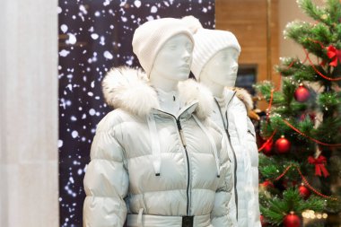 Yeni yıl vitrininde şık kışlık beyaz giysili erkek ve kadın mankenler..