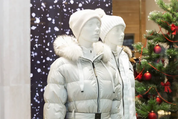 Yeni yıl vitrininde şık kışlık beyaz giysili erkek ve kadın mankenler..