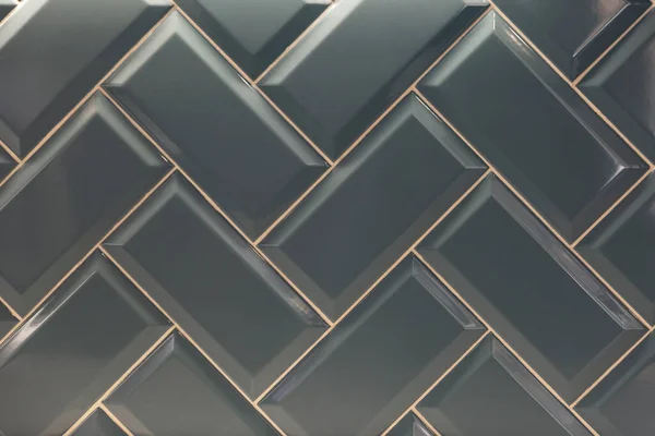 Herringbone decorative tiles. Glossy gray finishing material. Front view. Background. Space for text.