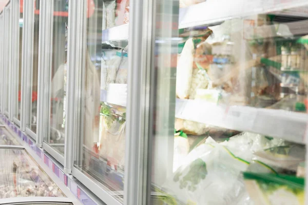 Frozen food in glass refrigerators in a supermarket. Close-up. Side view. Selective focus.