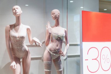 Bir iç çamaşırı mağazasının vitrininde indirim duyurusu yapan mankenler. Güzellik ve moda.