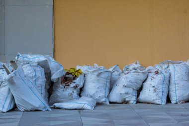 Sokakta içi harabe dolu beyaz plastik torbalar. İnşaat atıkları. Tadilat israfı. Kirlilik.