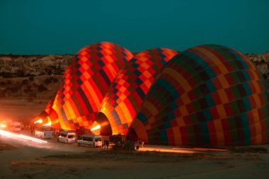 Sıcak hava balonları Kapadokya 'da güneş doğarken uçmaya hazırlanıyor. Sıcak hava balonlarına sıcak hava üflüyor.. 